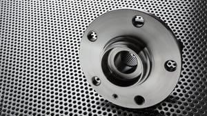 Metal wheel hub bearing on perforated steel surface.