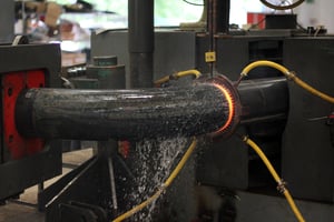 Photo showing a bent steel bar being induction hardened